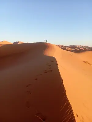 a group of people standing on top of a sand dune at Merzouga morocco in Tisserdmine