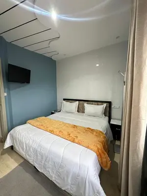 a bedroom with a bed with an orange blanket on it at Gîte - Auberge PYRAMIDES Bab Boudir in Bab Boudir