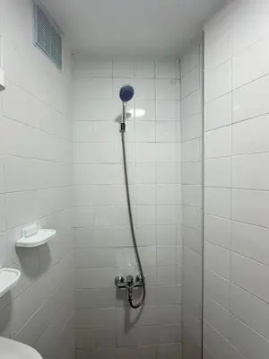 a shower in a white tiled bathroom with a toilet at Gîte - Auberge PYRAMIDES Bab Boudir in Bab Boudir