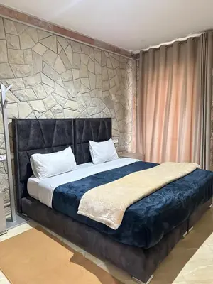 a bedroom with a large bed with a stone wall at Gîte - Auberge PYRAMIDES Bab Boudir in Bab Boudir