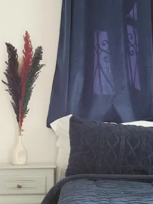 a bed with a blue curtain and a vase on a night stand at Ourika Valley Haven - Breathe, Relax, Unwind in Ourika