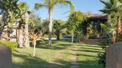 a yard with palm trees and a house at Villa les Portes de l'Atlas - MARRAKECH in Marrakech