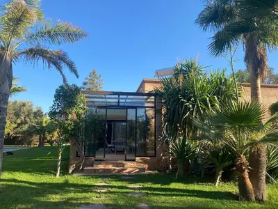 a house with glass doors and palm trees at Villa les Portes de l'Atlas - MARRAKECH in Marrakech