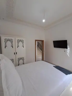 a bedroom with a white bed and a flat screen tv at Villa Hamza Marrakech in Bou Touil