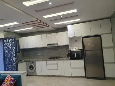 a large kitchen with white cabinets and a refrigerator at Guest house in Imouzzer Kandar