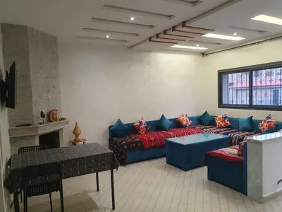 a living room with a blue couch and a table at Guest house in Imouzzer Kandar
