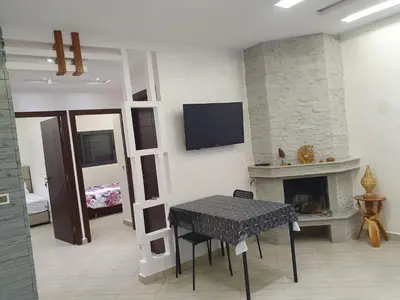 a living room with a table and a fireplace at Guest house in Imouzzer Kandar