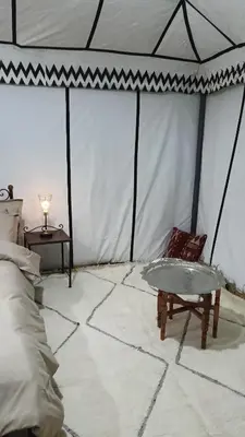 a room with a tent with a bed and a table at Akwabir camp in El Gouera