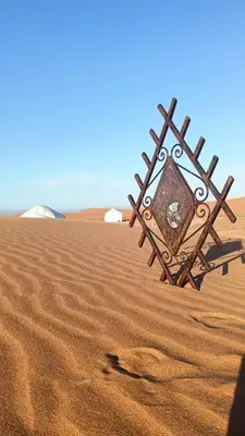 a sign in the sand in the desert at Akwabir camp in El Gouera
