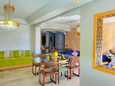 a dining room and living room with a table and chairs at Havre chic au cœur du centre-ville, à deux pas de la gare, espace généreux in Fès