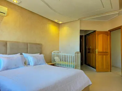 a bedroom with a white bed and a wooden door at Havre chic au cœur du centre-ville, à deux pas de la gare, espace généreux in Fès