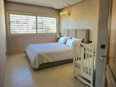 a bedroom with a bed and a window and a crib at Havre chic au cœur du centre-ville, à deux pas de la gare, espace généreux in Fès