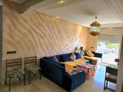 a living room with a blue couch and a table at Havre chic au cœur du centre-ville, à deux pas de la gare, espace généreux in Fès