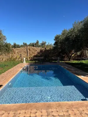 a swimming pool with a picnic table in the background at Villa SANDI in Ouled el guerne