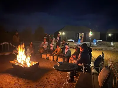 a group of people sitting around a fire at Merzouga Border Camp in Merzouga