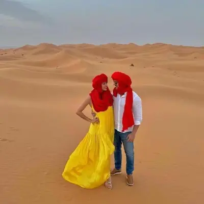 a man and woman standing in the desert at Merzouga Border Camp in Merzouga