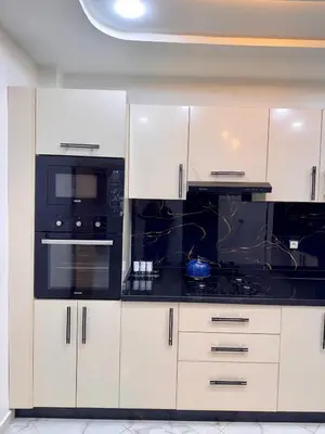 a kitchen with white cabinets and black appliances at Appartement deux chambres avec parking gratuit in Azrou