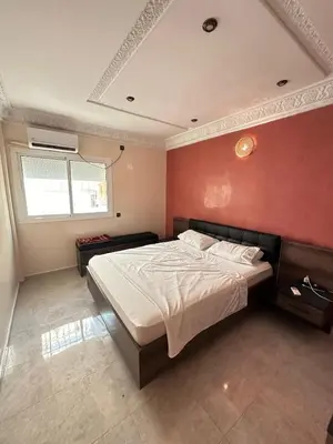 a bedroom with a large bed with a red wall at Fez Spacious Stay with Moroccan Artisanal Charm in Fès