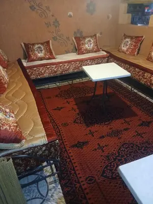 a room with two beds and a table on a rug at Appartement Aboumalik in Agdz