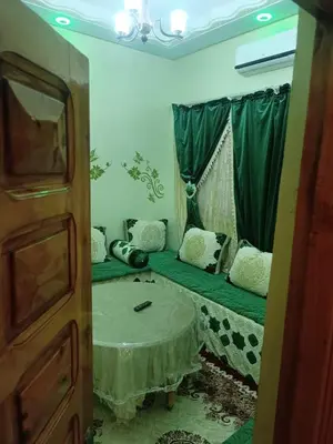 a room with a green bed with a table in it at Appartement Aboumalik in Agdz