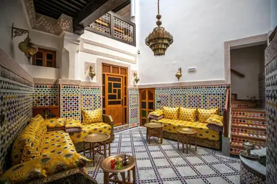 a living room with yellow couches and tables in a room at Dar derb el miter in Fès