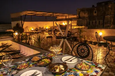 a table with plates of food on a balcony at night at Dar derb el miter in Fès