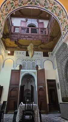 a room with a table and a balcony in a building at Dar Na in Station Bab Ftouh