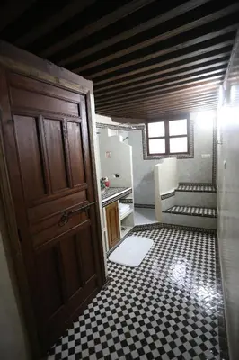 a bathroom with a door and a checkered floor at Dar Na in Station Bab Ftouh