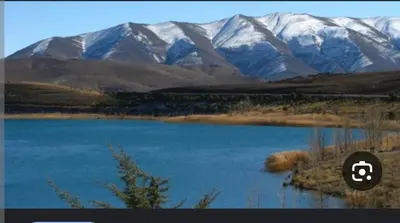 a picture of a lake with snowy mountains in the background at auberge arhal lac tislit in Bou Tarhbalout