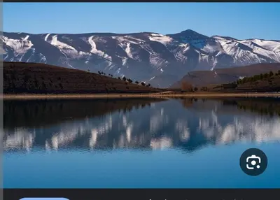 a reflection of snow covered mountains in a lake at auberge arhal lac tislit in Bou Tarhbalout