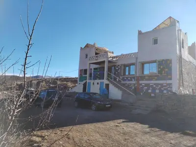 a house with a car parked in front of it at auberge arhal lac tislit in Bou Tarhbalout