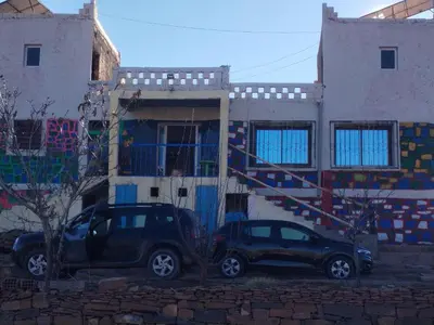 two cars parked in front of a building with a mural at auberge arhal lac tislit in Bou Tarhbalout