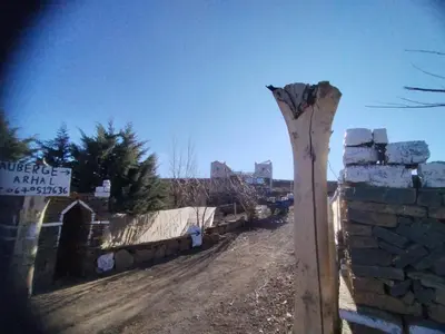 a wooden pole on a dirt road next to a stone wall at auberge arhal lac tislit in Bou Tarhbalout