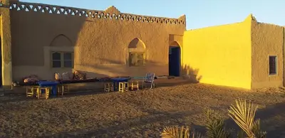 a yellow building with tables and chairs in front of it at Sahara Desert Activites in Merzouga