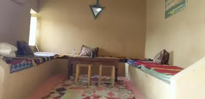 a room with two beds and a table and chairs at Sahara Desert Activites in Merzouga