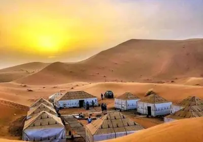 a group of tents in the desert with a sunset at Sahara Desert Activites in Merzouga