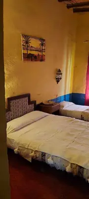a bedroom with two beds and a painting on the wall at hostel sable dor merzouga in Merzouga