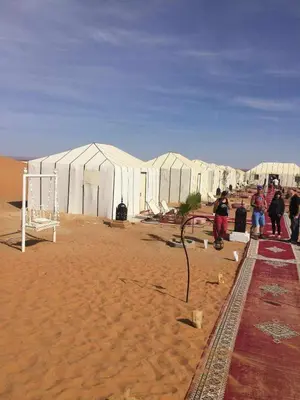 a group of people standing in front of tents in the desert at jumeirah resort luxury desert camp in Merzouga