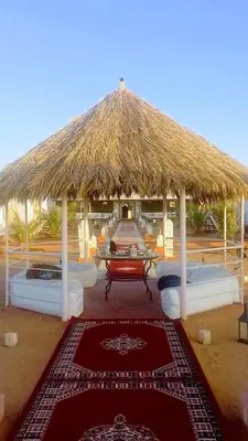 a pavilion with four beds and a straw roof at jumeirah resort luxury desert camp in Merzouga