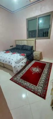 a bedroom with a bed and a red rug on the floor at Superbe appartement de luxe in Fès