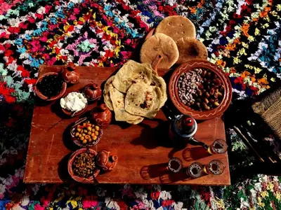 a wooden table topped with different types of food on a rug at Gite entre les deux vallées in Tacheddirt