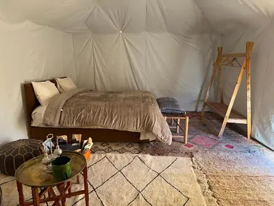 a bedroom with a bed and a table in a tent at Across Sahara in Bou Nou