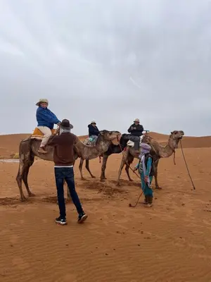 a group of people riding on camels in the desert at Across Sahara in Bou Nou