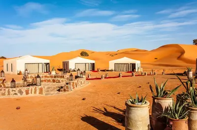 a group of tents in the desert with sand dunes at Quiet Luxury Camp in Merzouga