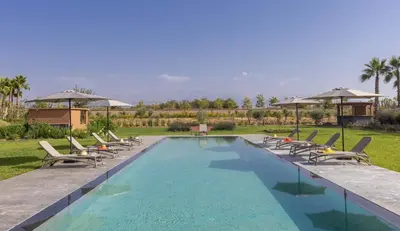 a swimming pool with chairs and umbrellas at Villa Dar Tillili Marrakech in Heddad