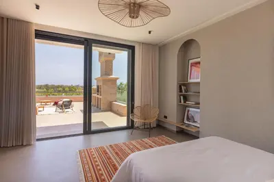 a bedroom with a bed and a view of a patio at Villa Dar Tillili Marrakech in Heddad