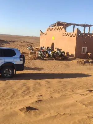 a group of motorcycles parked next to a building in the desert at auberge lac iriki in Foum Zguid