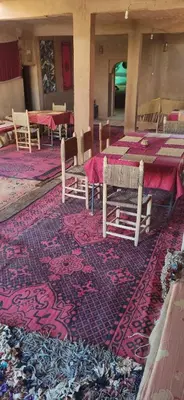 a room with tables and chairs on a rug at auberge lac iriki in Foum Zguid