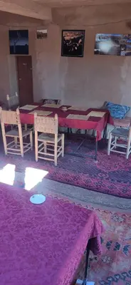 a room with a table and chairs on a purple rug at auberge lac iriki in Foum Zguid