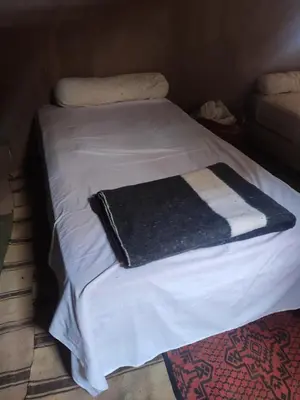 a white bed with a black and white blanket on it at auberge lac iriki in Foum Zguid